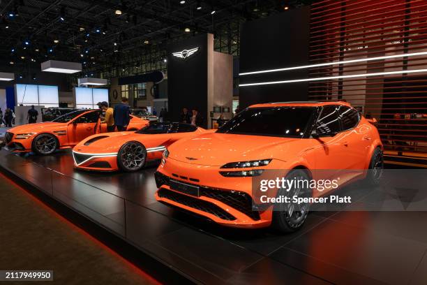 People walk by Genesis's new electric vehicles, including the Neolun Concept and the GV60 Magma Concept, at the New York International Auto Show on...
