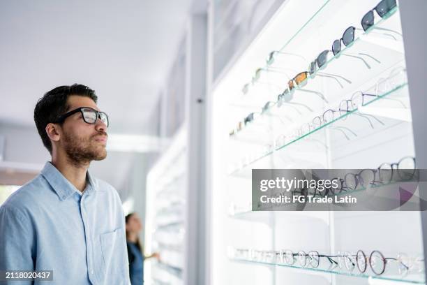 giovane che compra un occhiale al negozio di ottica - provare foto e immagini stock