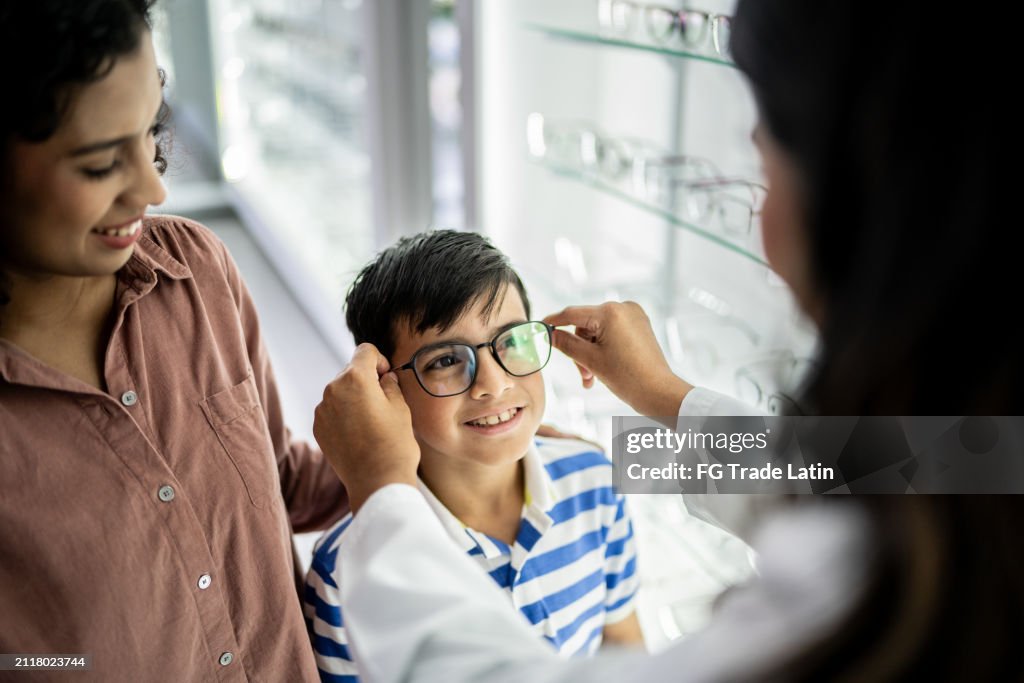 Mother and son buying a glasses and talking with optician at optical store