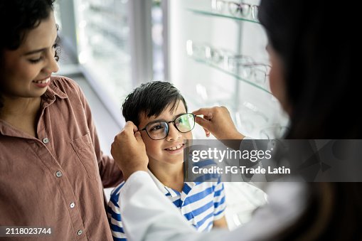 Mother and son buying a glasses and talking with optician at optical store Mother and son buying a glasses and talking with optician at optical store