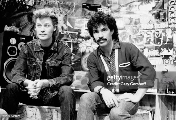 View of American Pop musicians Daryl Hall and John Oates, both of the duo Hall & Oates, as they sit on a low stage during an interview on MTV at...