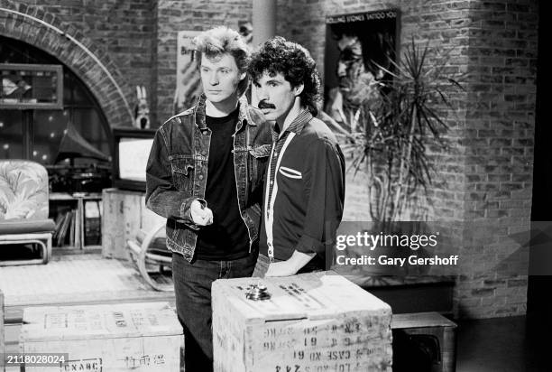 View of American Pop musicians Daryl Hall and John Oates as they stand behind several crates during an interview on MTV at Teletronic Studios, New...