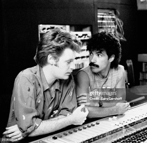 View of Pop musicians Daryl Hall and John Oates, both of the duo Hall & Oates, seated a mixing console as they talk during a recording of their 'H2O'...