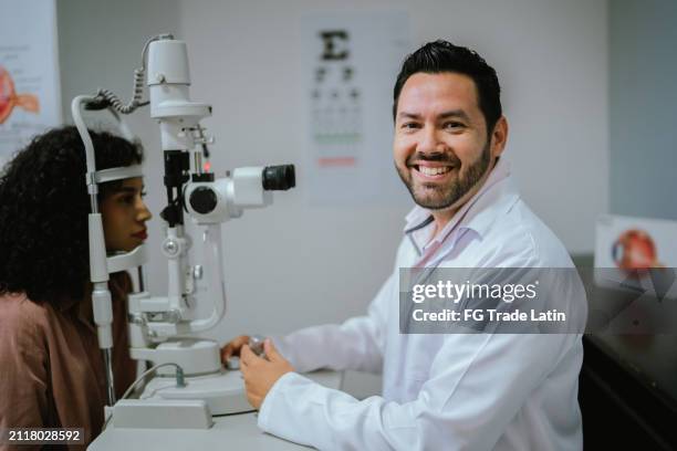 portrait of a mid adult ophthalmologist man doing exam on patient at medical clinic - ophthalmologist stock pictures, royalty-free photos & images