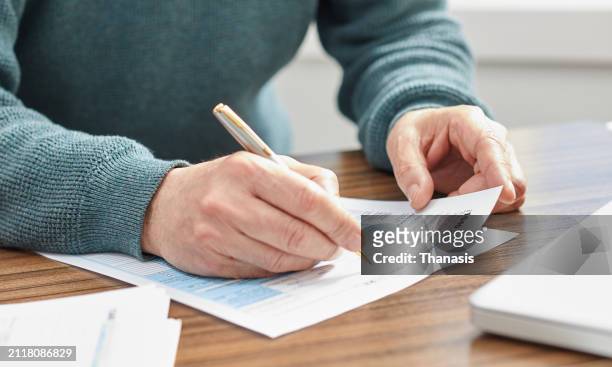 close-up of a man holding a tax form, working from home - us federal trade commission stock pictures, royalty-free photos & images