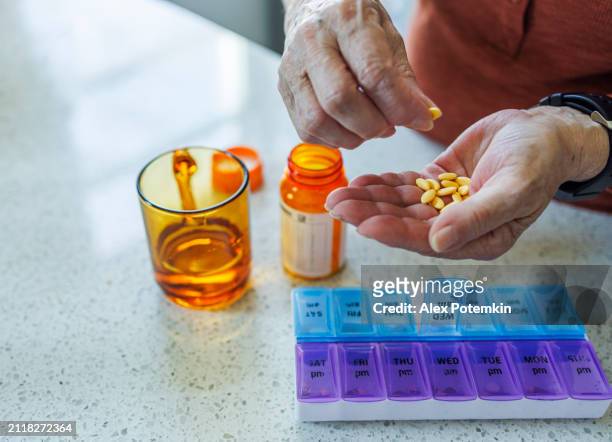 health routine control: senior woman hand putting pill capsules from the box to a weekly dose organizer. - weekly stock pictures, royalty-free photos & images