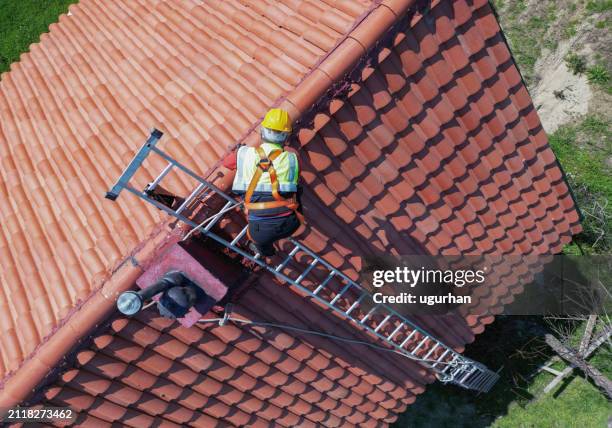 worker doing roof repair with safety. - telhado imagens e fotografias de stock