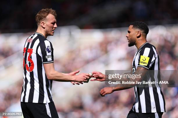 Jamaal Lascelles of Newcastle United passes Dan Burn of Newcastle United the captains armband as he goes off injured during the Premier League match...