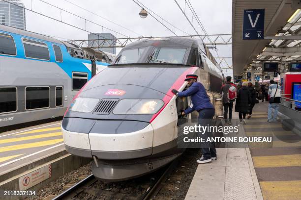 Controller opening a hatch that opens the cover of the automatic coupler to couple to another TGV High-speed train seen from the platform of...