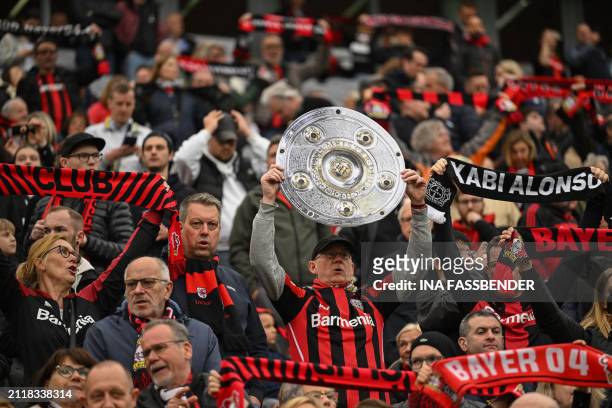 Bayer Leverkusen fan holds up a mock-up of the Bundesliga trophy prior to the German first division Bundesliga football match Bayer 04 Leverkusen v...