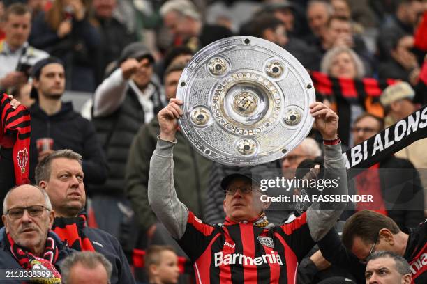 Bayer Leverkusen fan holds up a mock-up of the Bundesliga trophy prior to the German first division Bundesliga football match Bayer 04 Leverkusen v...