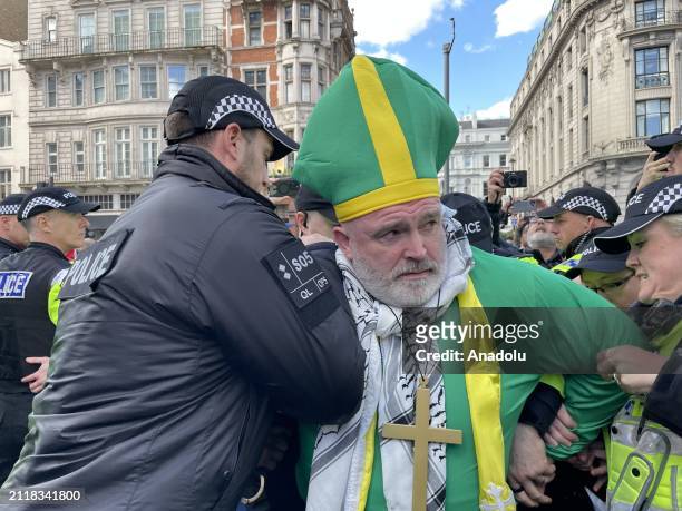 Police officers take a demonstrator into custody as a large number of people gather in the British capital on Saturday to protest Israeli attacks and...