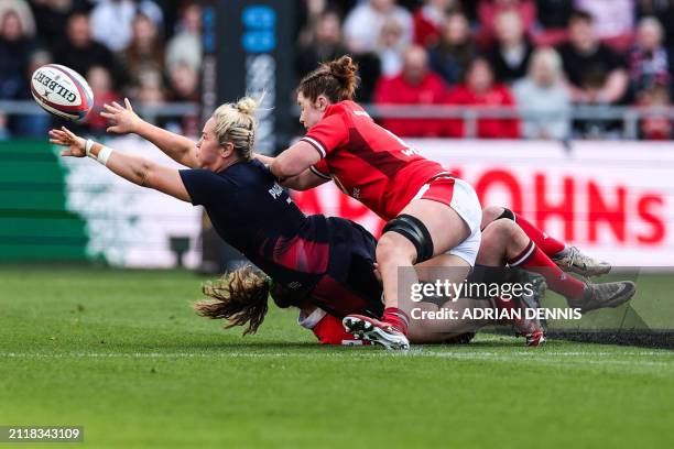 England's flanker Marlie Packer passes the ball as she is tackled by Wales' wing Carys Cox and Wales' flanker Kate Williams during the Six Nations...