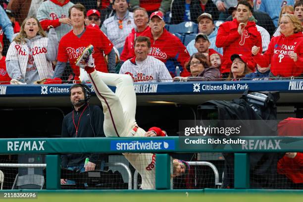 First baseman Bryce Harper of the Philadelphia Phillies chases a foul ball hit by Austin Riley of the Atlanta Braves and flips over the dugout...