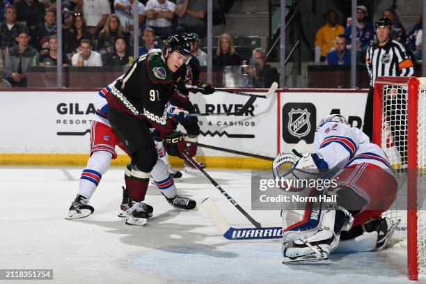 Josh Doan of the Arizona Coyotes skates with the puck as Jonathan Quick of the New York Rangers gets ready to make a save during the first period of...