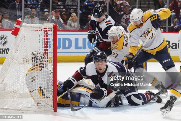 Mikko Rantanen of the Colorado Avalanche collides with goaltender Kevin Lankinen of the Nashville Predators after being cross checked next to...