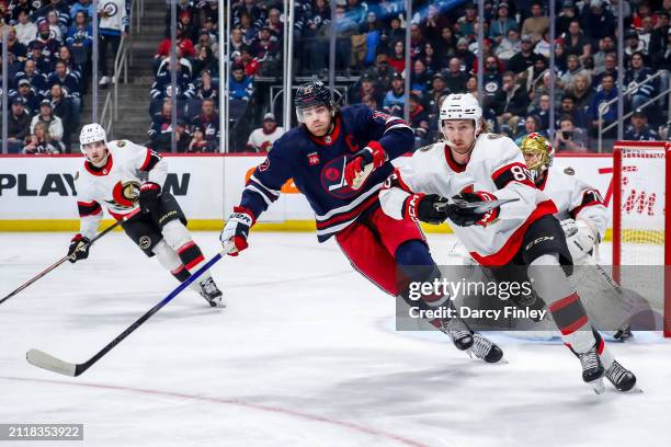 Adam Lowry of the Winnipeg Jets and Jake Sanderson of the Ottawa Senators follow the play up the ice during first period action at the Canada Life...