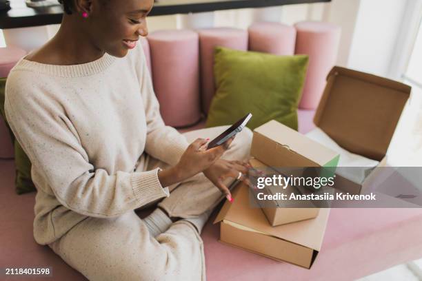 happy black woman checking online order and using smartphone app. - auspacken stock-fotos und bilder