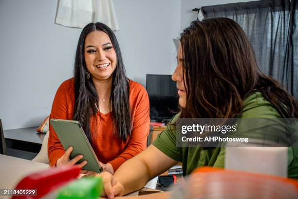 küchenverbindungen: frau teilt tablet-einblicke mit teenager - minderheit stock-fotos und bilder