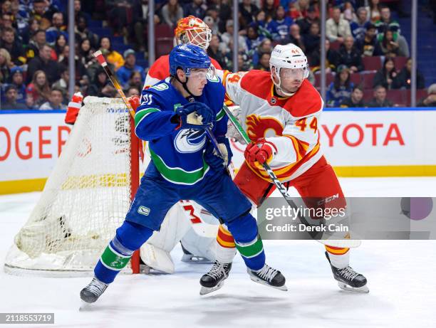 Joel Hanley of the Calgary Flames defends against Nils Hoglander of the Vancouver Canucks during the first period of their NHL game at Rogers Arena...