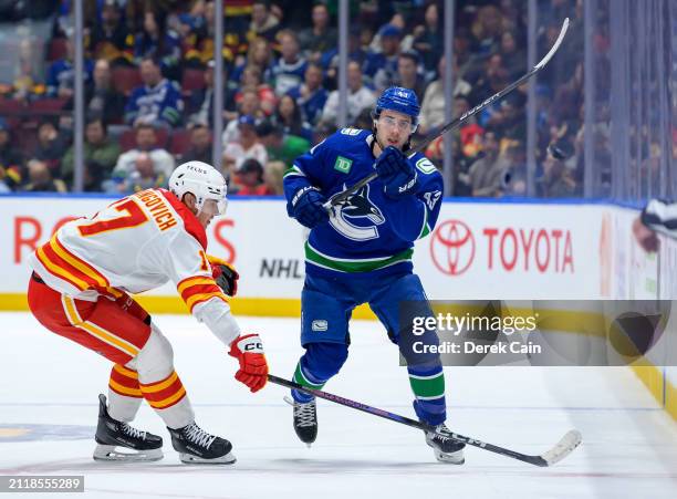 Yegor Sharangovich of the Calgary Flames defends against Quinn Hughes of the Vancouver Canucks during the first period of their NHL game at Rogers...