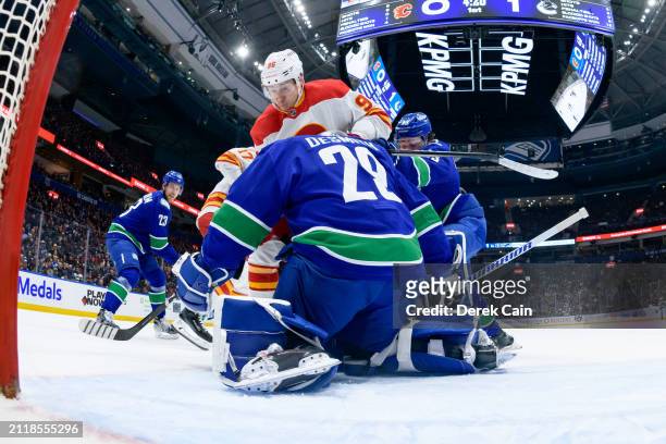 Casey DeSmith makes a save as Quinn Hughes of the Vancouver Canucks defend against Andrei Kuzmenko of the Calgary Flames during the first period of...