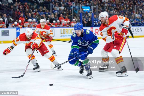 MacKenzie Weegar and Daniil Miromanov of the Calgary Flames defend against Conor Garland of the Vancouver Canucks during the third period of their...