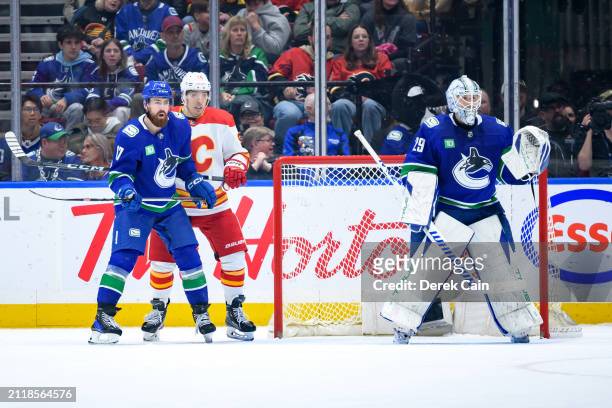 Filip Hronek and Casey DeSmith of the Vancouver Canucks defend against Andrei Kuzmenko of the Calgary Flames during the third period of their NHL...