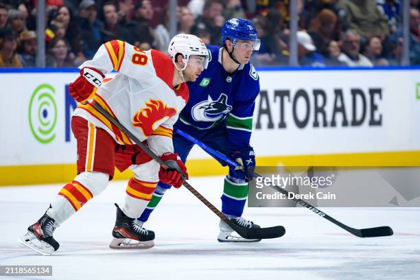Andrew Mangiapane of the Calgary Flames and Nils Hoglander of the Vancouver Canucks skate during the third period of their NHL game at Rogers Arena...