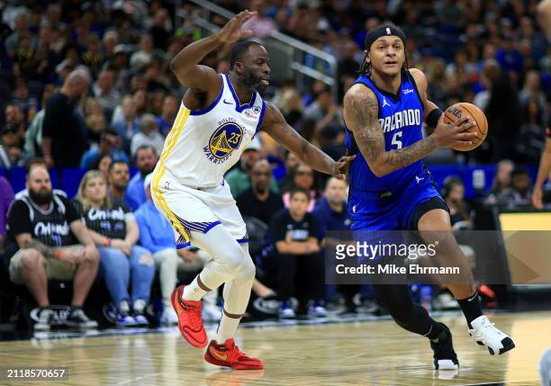 Paolo Banchero of the Orlando Magic drives to the basket on Draymond Green of the Golden State Warriors during a game at Kia Center on March 27, 2024...