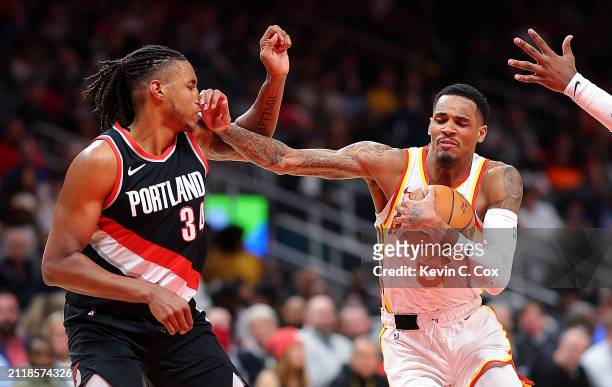 Dejounte Murray of the Atlanta Hawks drives between Jabari Walker and Scoot Henderson of the Portland Trail Blazers during the fourth quarter at...