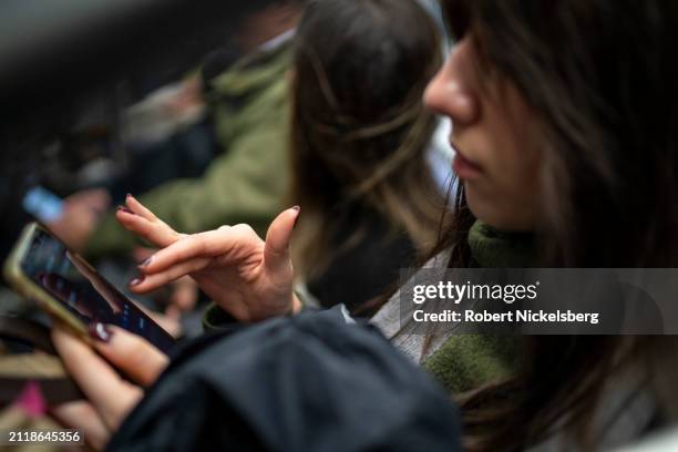 Subway passenger reads her iPhone March 27, 2024 in New York City. New York City's subway daily ridership is approximately 3.2 million riders.