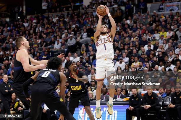 Devin Booker of the Phoenix Suns puts up a shot against Nikola Jokic, Peyton Watson and Kentavious Caldwell-Pope of the Denver Nuggets during the...