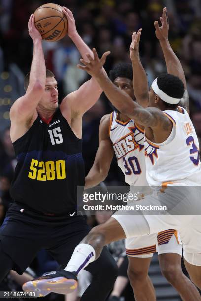 Nikola Jokic of the Denver Nuggets is guarded by Thaddeus Young and Bradley Beal of the Phoenix Suns during the first quarter at Ball Arena on March...
