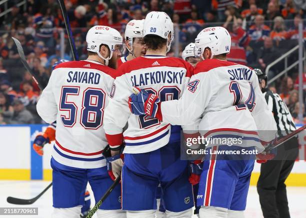 David Savard, Juraj Slafkovsky, and Nick Suzuki of the Montreal Canadiens discuss the power play in the second period against the Edmonton Oilers on...
