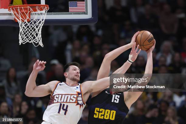 Drew Eubanks of the Phoenix Suns fights for a rebound against Nikola Jokic of the Denver Nuggets during the third quarter at Ball Arena on March 27,...