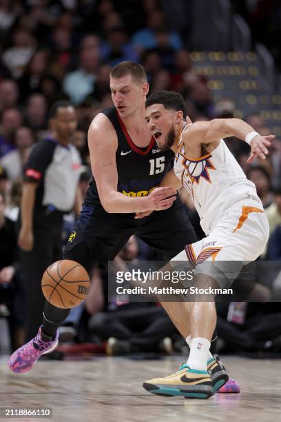 Devin Booker of the Phoenix Suns loses the ball against Nikola Jokic of the Denver Nuggets during the third quarter at Ball Arena on March 27, 2024...
