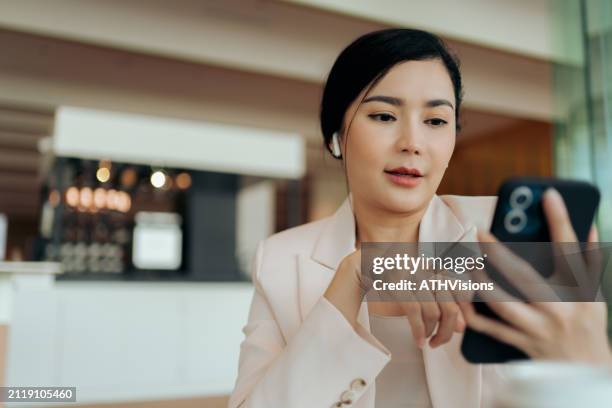 asiatische geschäftsfrau mit smartphone und digitalem tablet in modernen büroräumen. remote workplace mit flexibilität. digitaler nomade - mitarbeiterbindung stock-fotos und bilder
