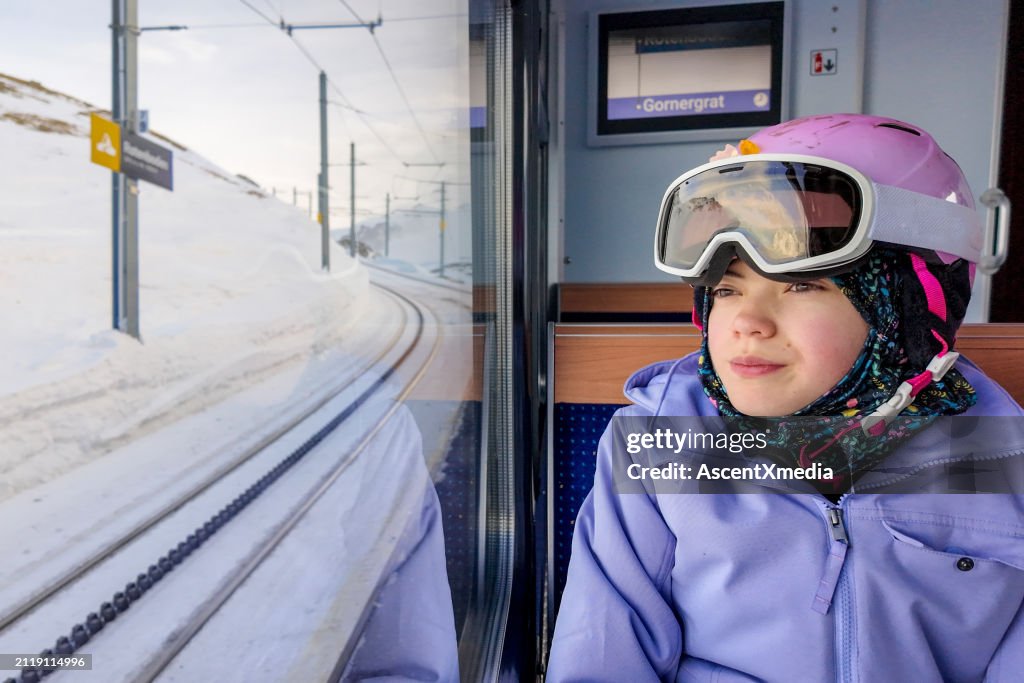 Junge Skifahrerin schaut aus dem Fenster des Zuges