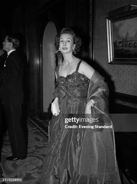 British fashion model Barbara Goalen wearing an evening dress and hoop earrings, October 20th 1953.