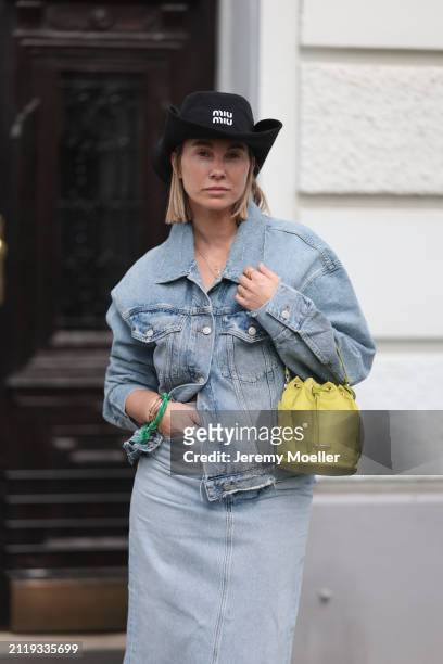 Karin Teigl seen wearing Miu Miu black cowboy hat, Agolde light blue denim jacket, Agolde light blue denim long skirt, Miu Miu green bracelet, Prada...
