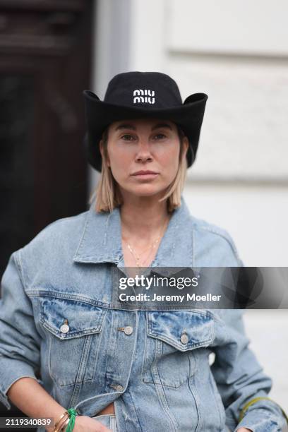 Karin Teigl seen wearing Miu Miu black cowboy hat, Agolde light blue denim jacket, Miu Miu green bracelet, on March 23, 2024 in Munich, Germany.