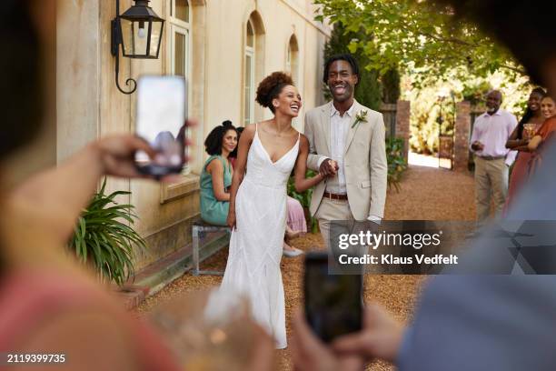 cheerful bride and groom holding hands at party - photo messaging stock pictures, royalty-free photos & images