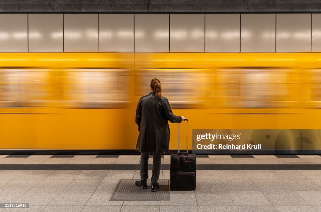 Rear view of woman standing in front of arriving subway train