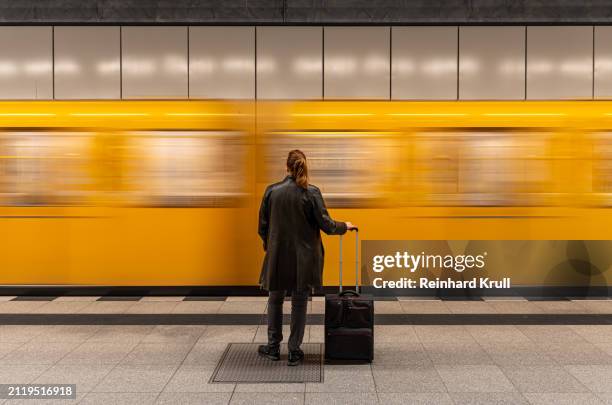 rear view of woman standing in front of arriving subway train - estação de metro imagens e fotografias de stock