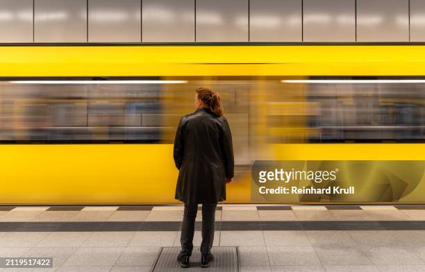 rear view of woman standing in front of arriving subway train - back of leather jacket stock pictures, royalty-free photos & images