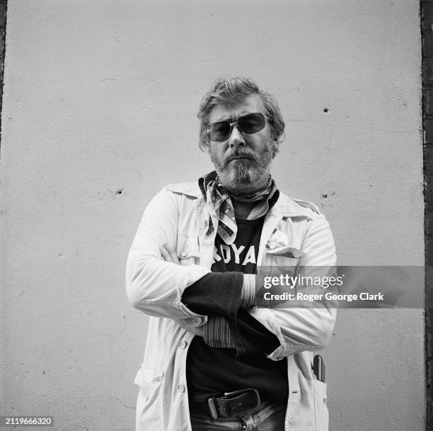 Playwright John Osborne wearing a Royal Court t shirt and sunglasses outside the Royal Court Theatre, London, circa 1975.