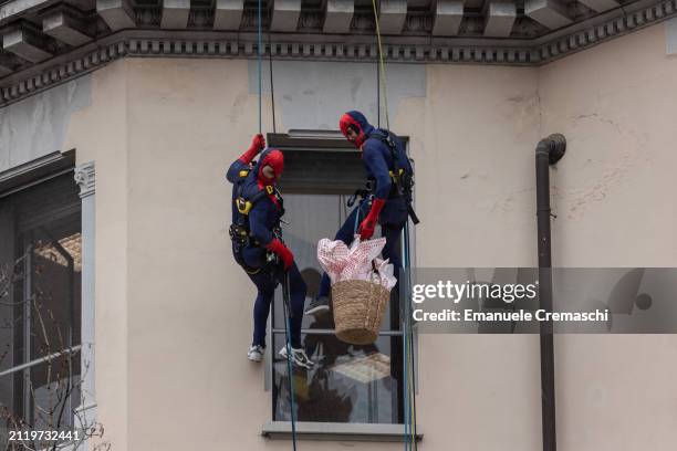 Rope access workers wearing comic-based superhero Spiderman costumes prepare to give chocolate Easter eggs to some relatives of hospitalized children...