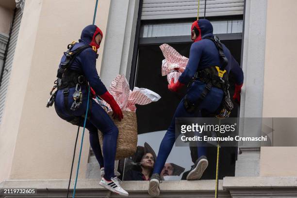 Rope access workers wearing comic-based superhero Spiderman costumes give chocolate Easter eggs to some relatives of hospitalized children at Clinica...