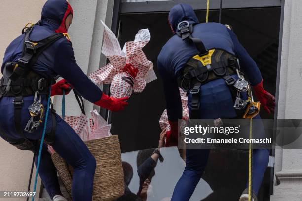 Rope access workers wearing comic-based superhero Spiderman costumes give chocolate Easter eggs to some relatives of hospitalized children at Clinica...